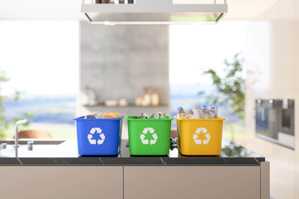 3 poubelles de recyclage sur un plan de travail de cuisine avec fenêtre en arrière-plan