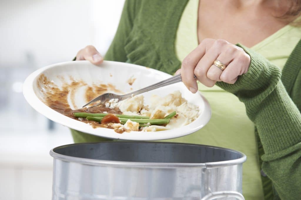 Femme en train de jeter des déchets alimentaires dans une poubelle